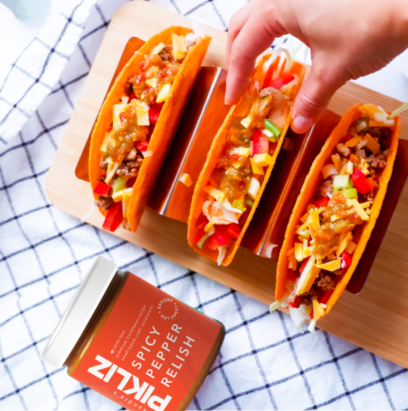 Alexandra’s Pikliz® Spicy Pepper Relish spooned onto grilled chicken tacos, showing vibrant vegetables, texture, and bold Haitian-Caribbean flavor